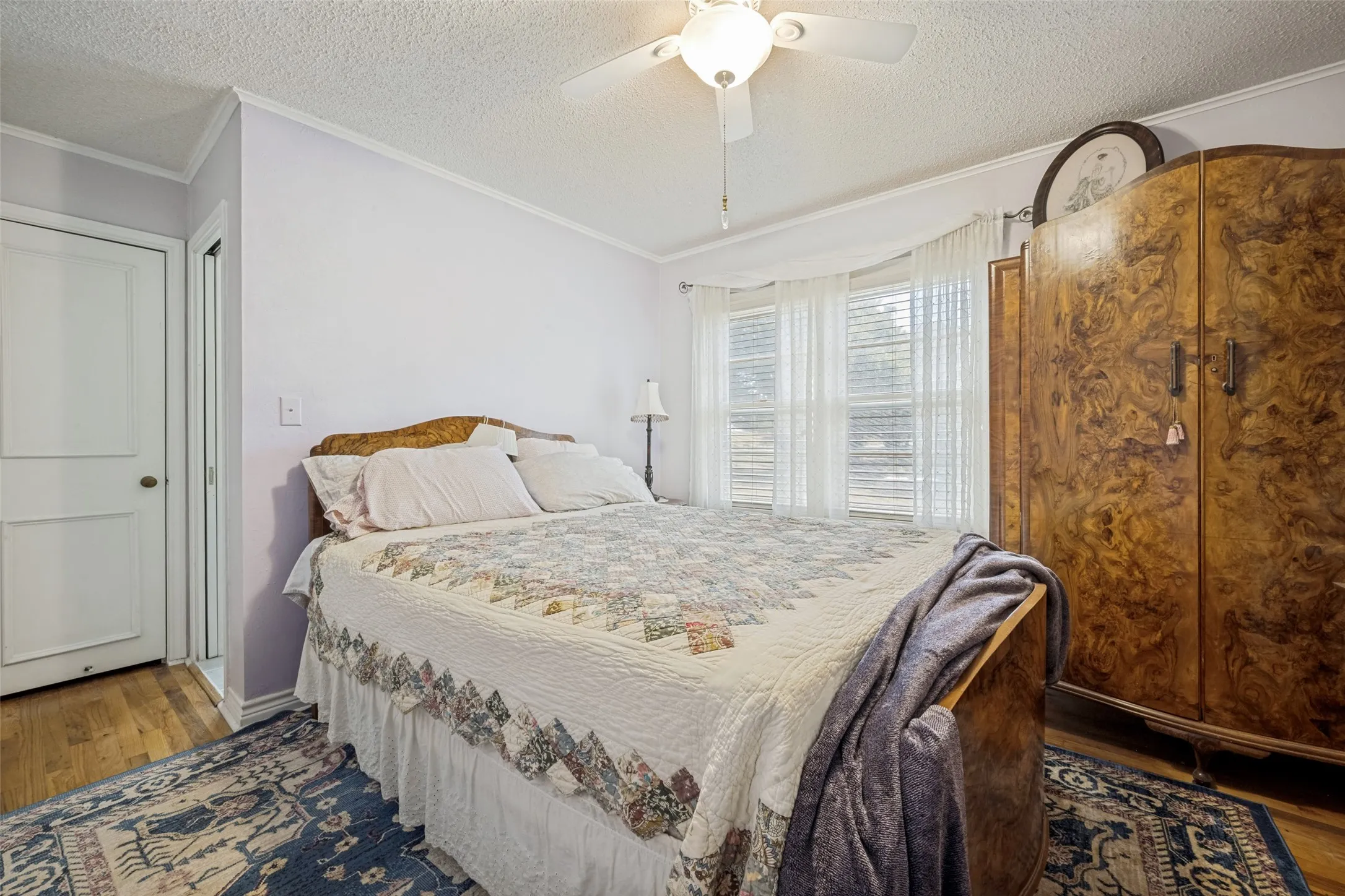Wood-finish flooring with white trim and a ceiling fan