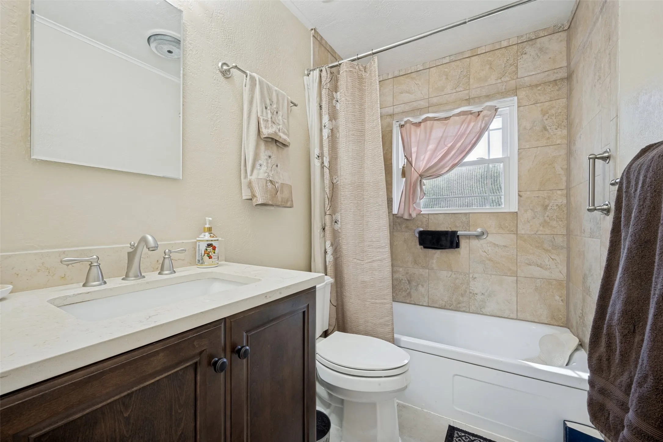 Vanity with a white countertop and undermount sink, brushed nickel faucet, wood-finish cabinetry, and a mirrored medicine cabinet