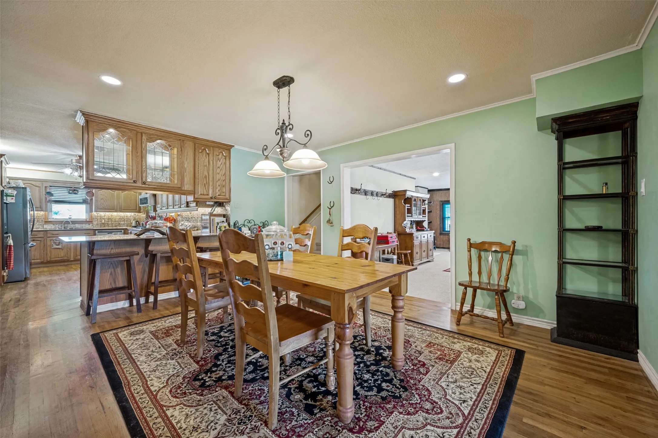 Wood-finish flooring throughout, with a kitchen featuring wood cabinetry, an island with seating, and recessed lighting