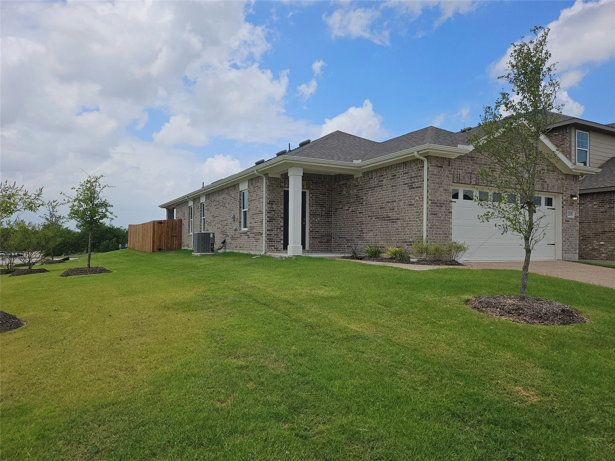 Brick exterior with a covered entry, white garage door, and a well-maintained lawn