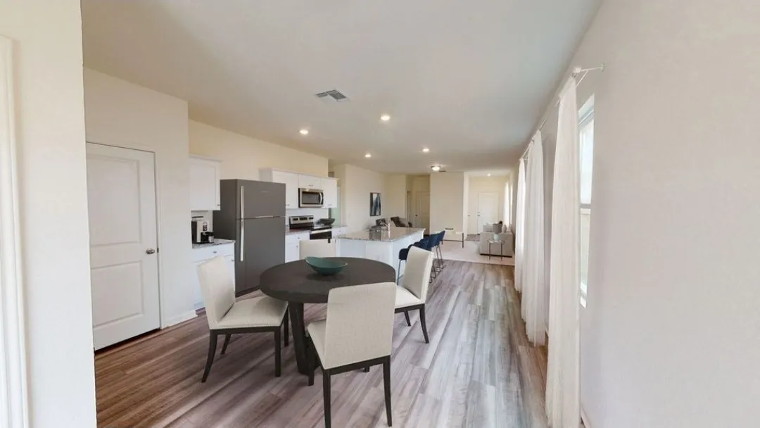 Integrated kitchen and dining area featuring wood-finish flooring, recessed lighting, and a kitchen island with seating