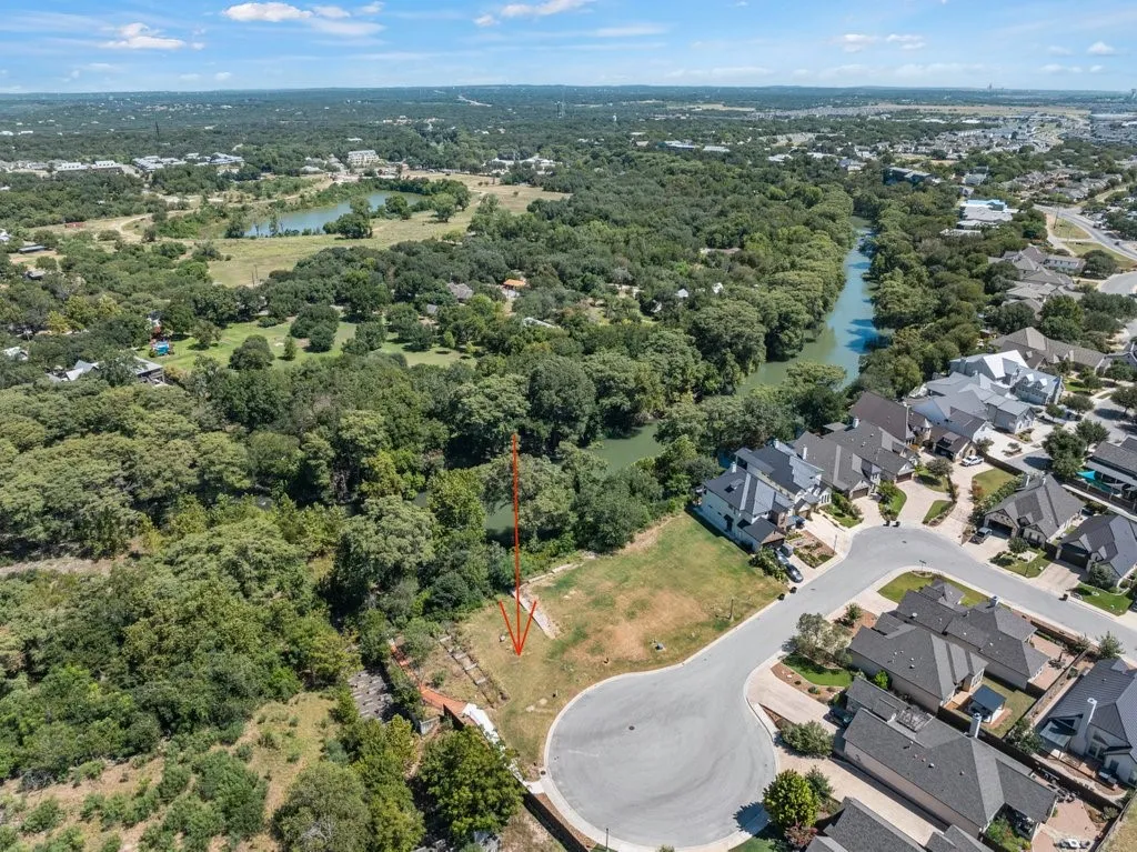Expansive residential lot with established trees and natural landscaping, bordering a natural waterway