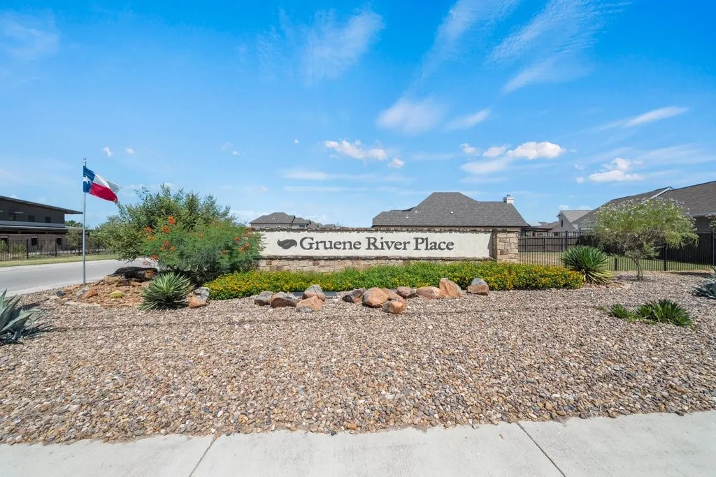 Community entrance sign featuring stone veneer and decorative landscaping