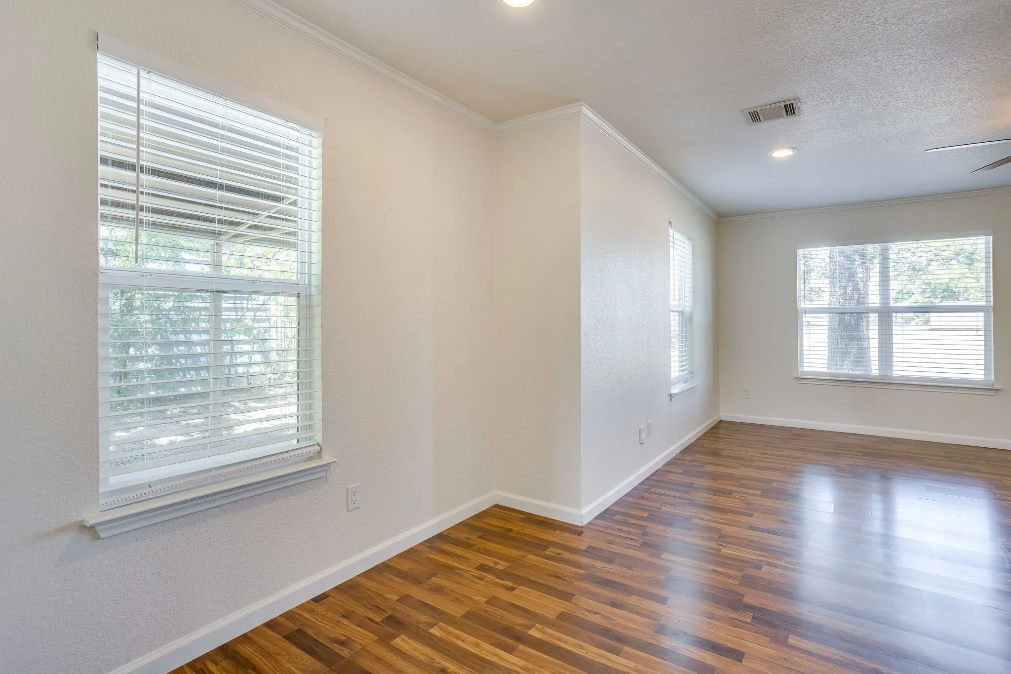 Wood laminate flooring, multiple windows with blinds, recessed lighting, and crown molding