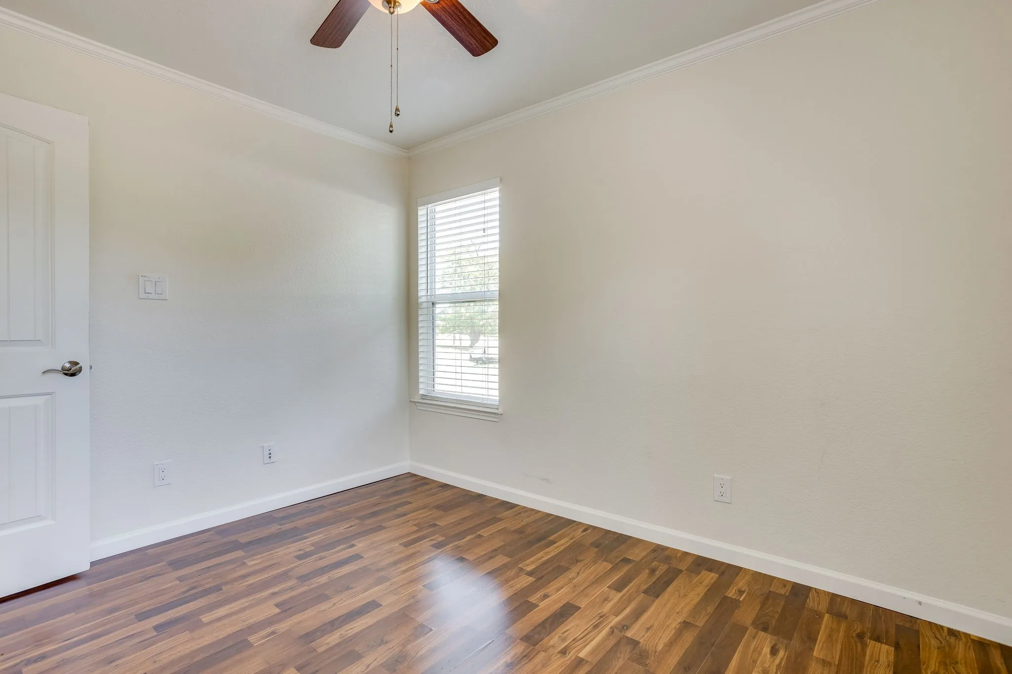 Wood laminate flooring, white walls, and a ceiling fan with light fixture