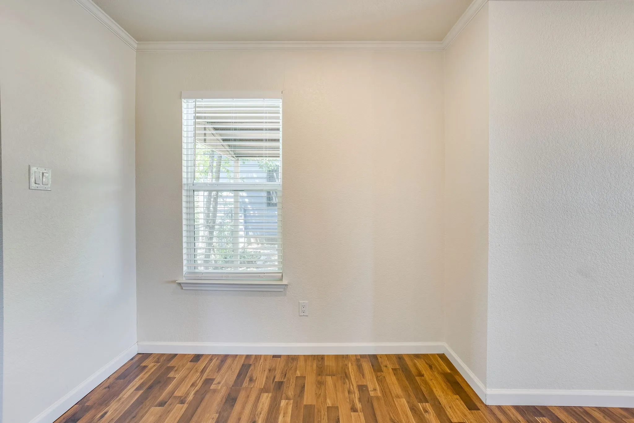 Wood laminate flooring with crisp white baseboards and crown molding