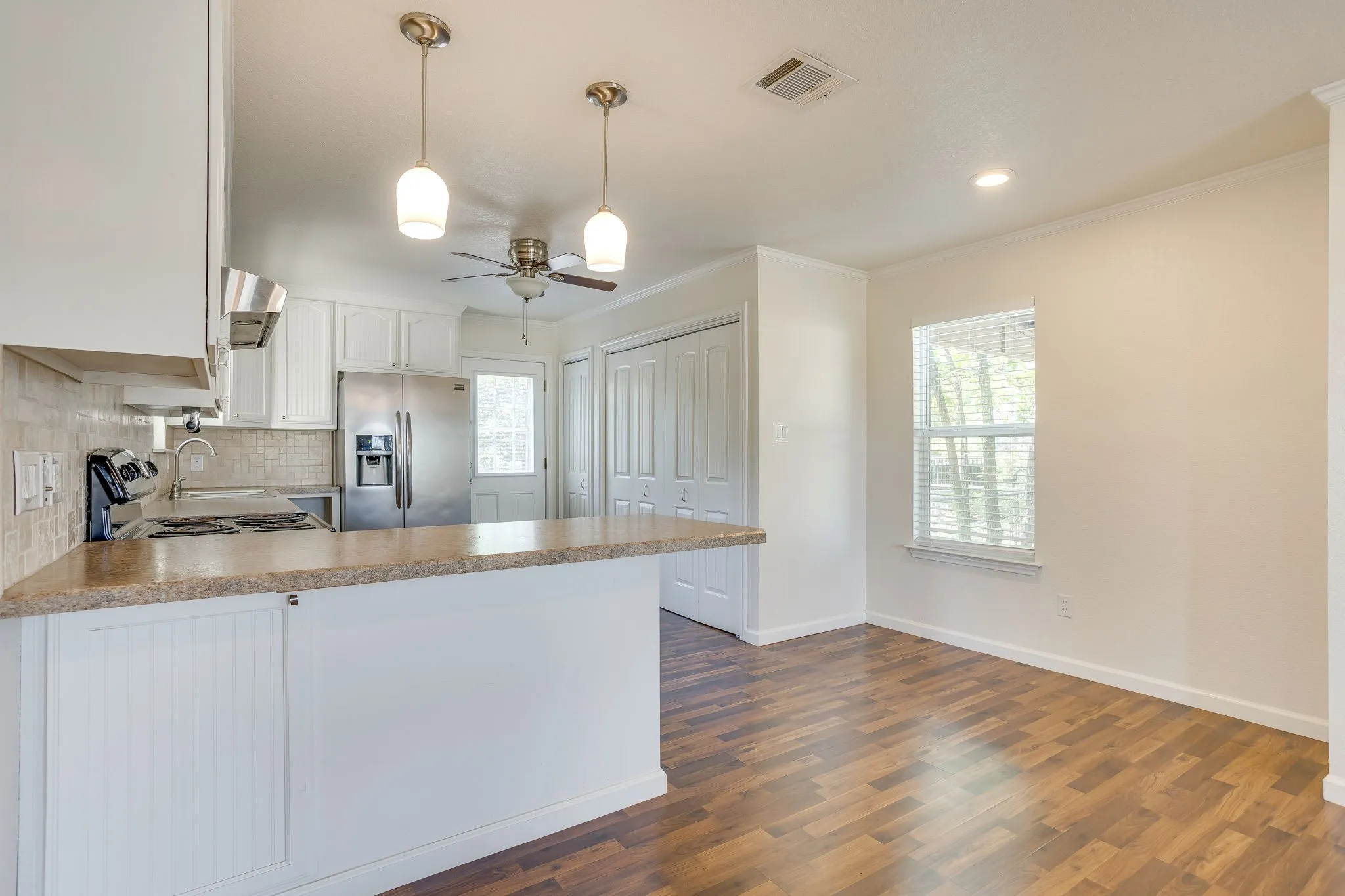 Kitchen area featuring white cabinetry, light-colored countertops, stainless steel appliances, and a tile backsplash