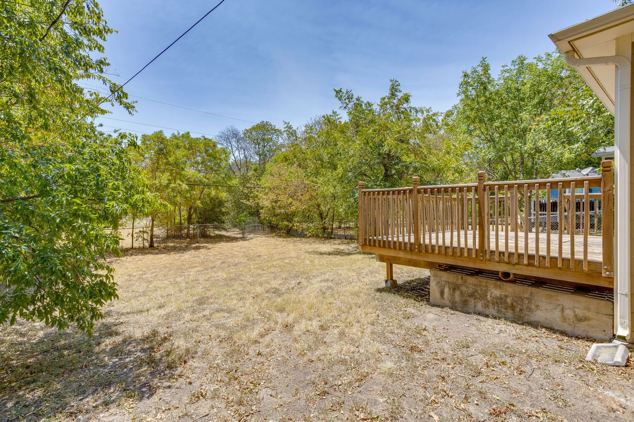 Expansive backyard with a wood deck, mature trees, and ample open space