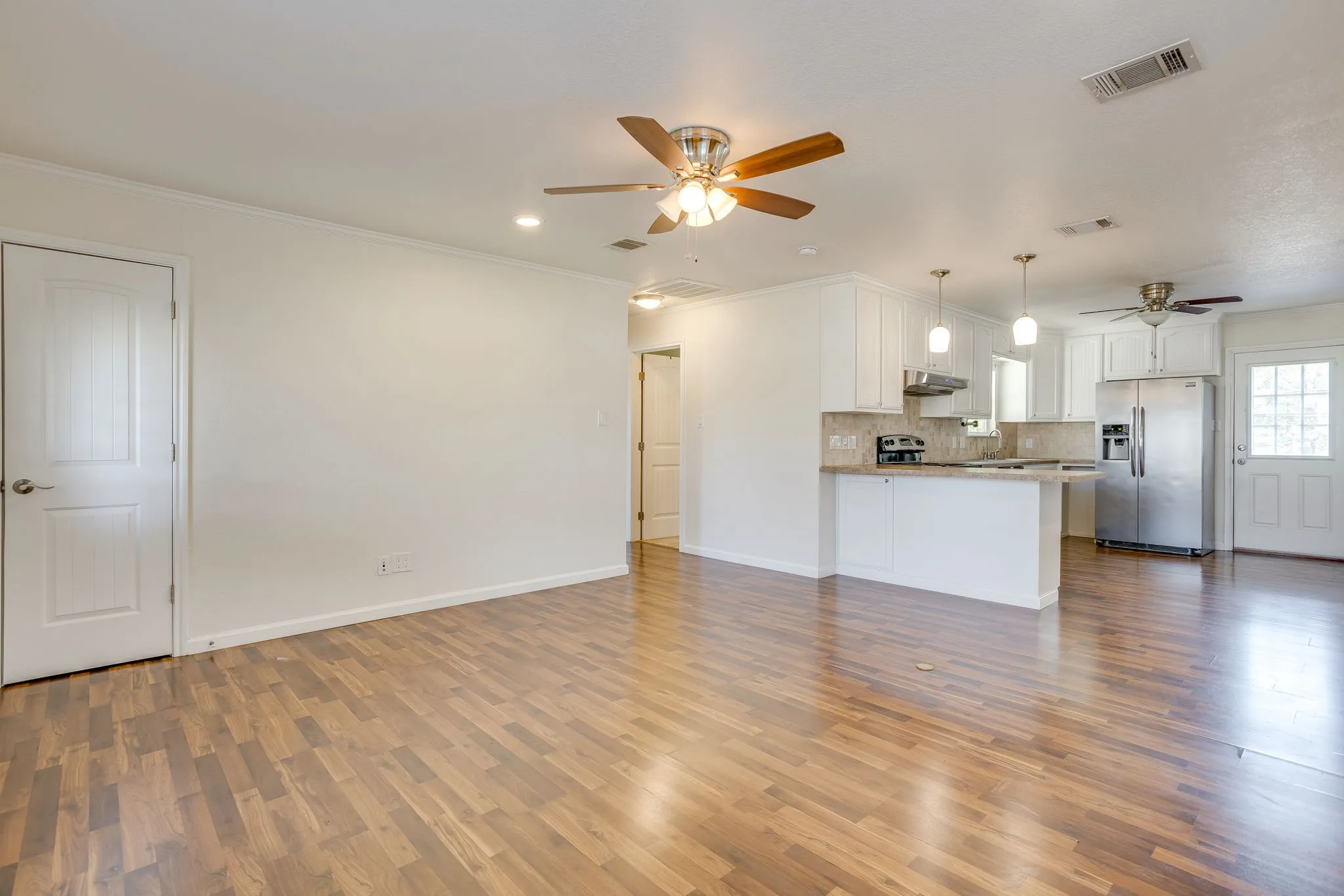 Wood laminate flooring throughout, bright white walls, recessed lighting, and ceiling fans