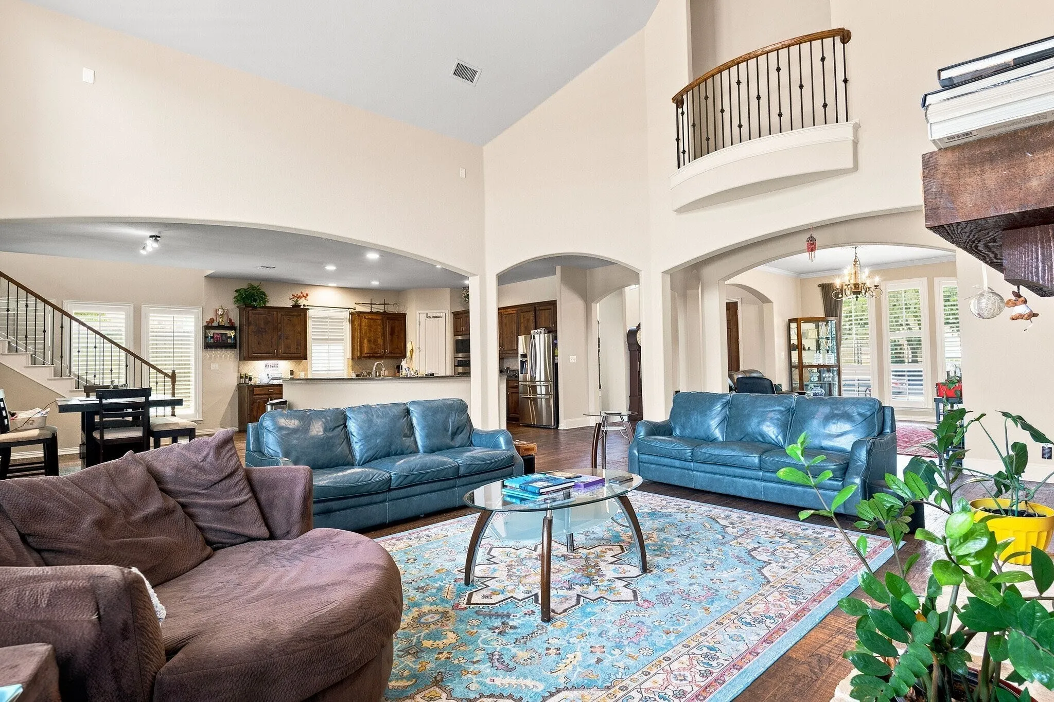Two-story living area featuring wood-finish flooring, arched doorways, a built-in balcony, and a multi-level ceiling