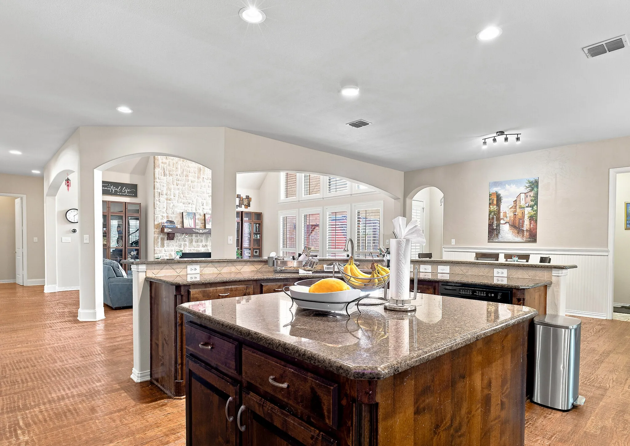 Kitchen featuring dual islands with stone countertops, recessed lighting, wood-finish flooring, and arched doorways