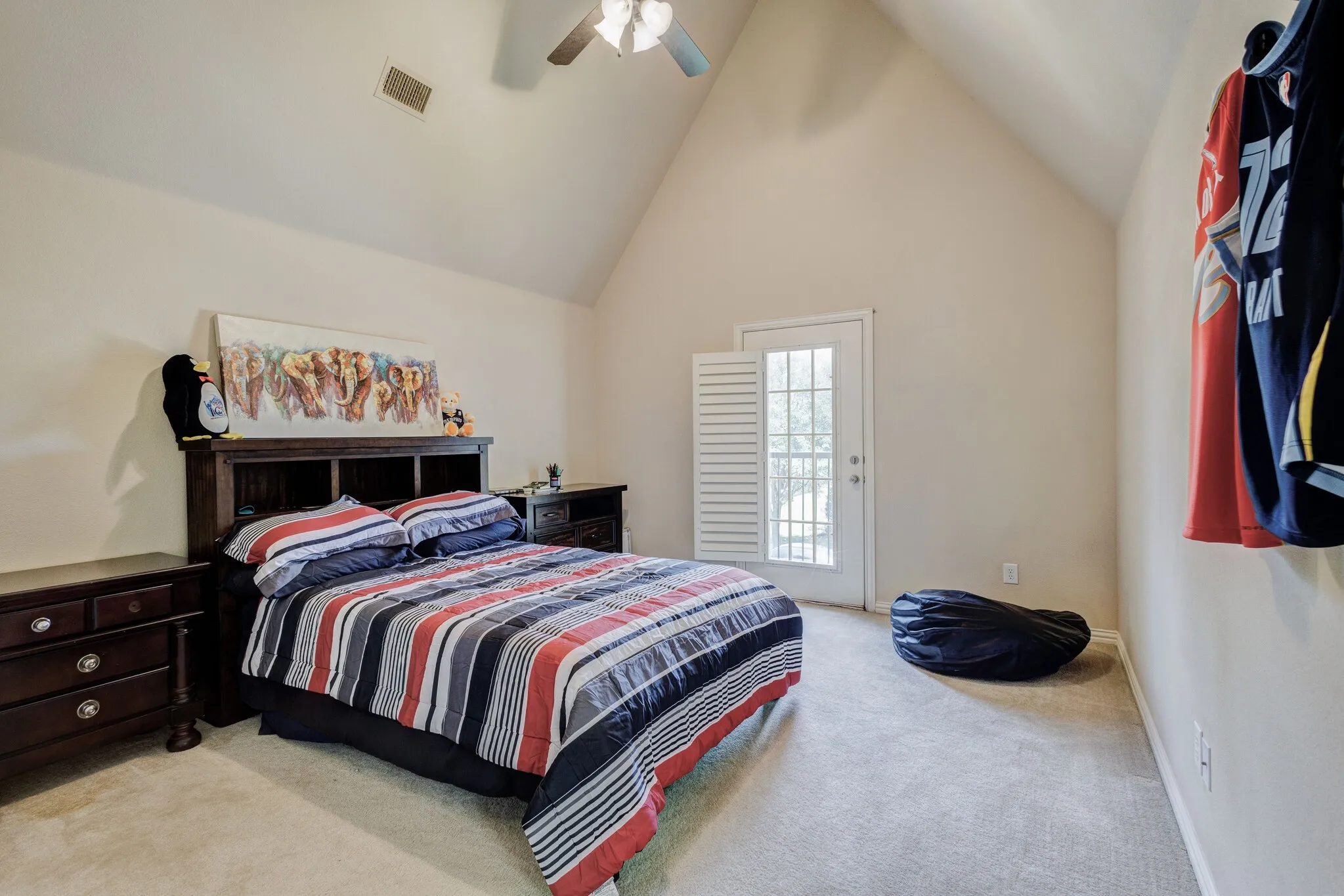 Vaulted ceiling with ceiling fan, light-toned carpeting, and a white door with glass panels