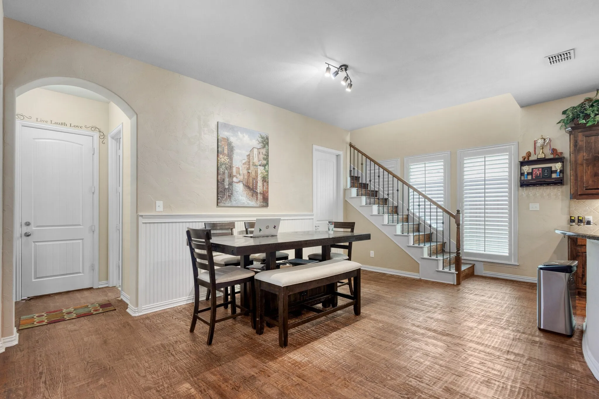Wood-finish flooring throughout, beadboard wall paneling, and an arched entryway