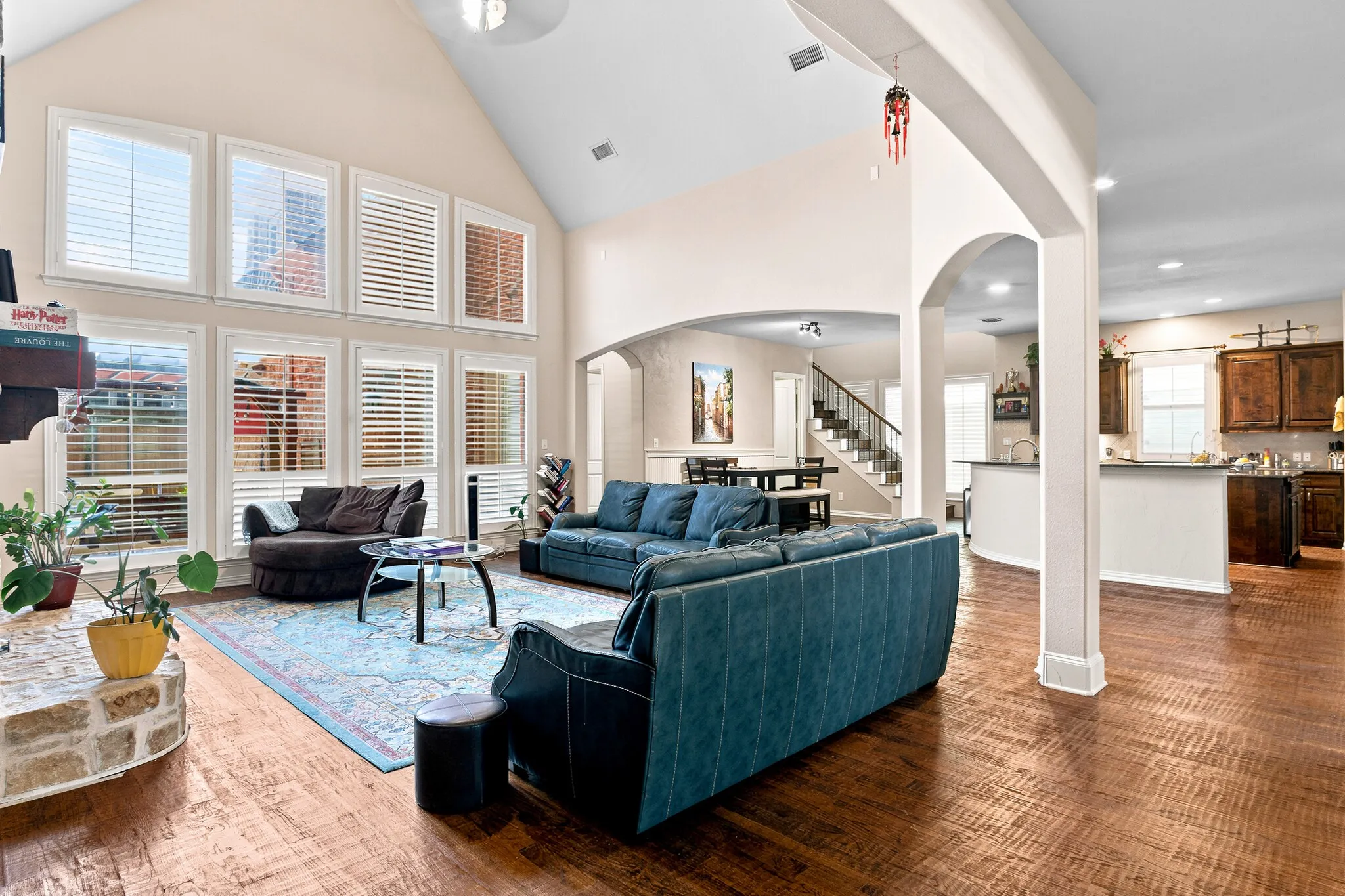 Vaulted ceilings, a stone fireplace, wood-finish flooring, and multiple arched doorways