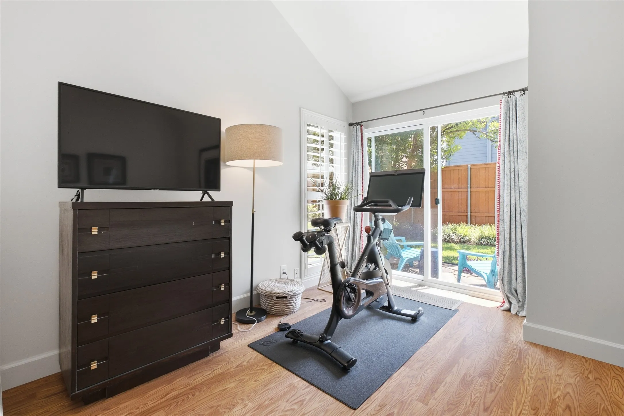 Another view of the primary suite, showing the sliding glass door, plantation shutters, and the natural light the room captures throughout the day.