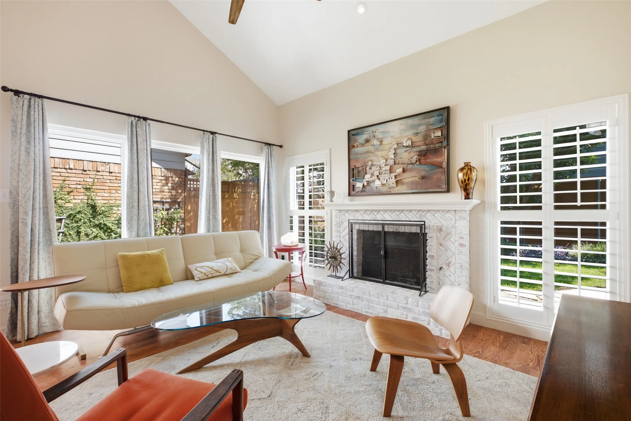 The herringbone brick fireplace anchors this living space while plantation shutters frame views of the backyard on either side. Plenty of natural light, no matter the time of day.