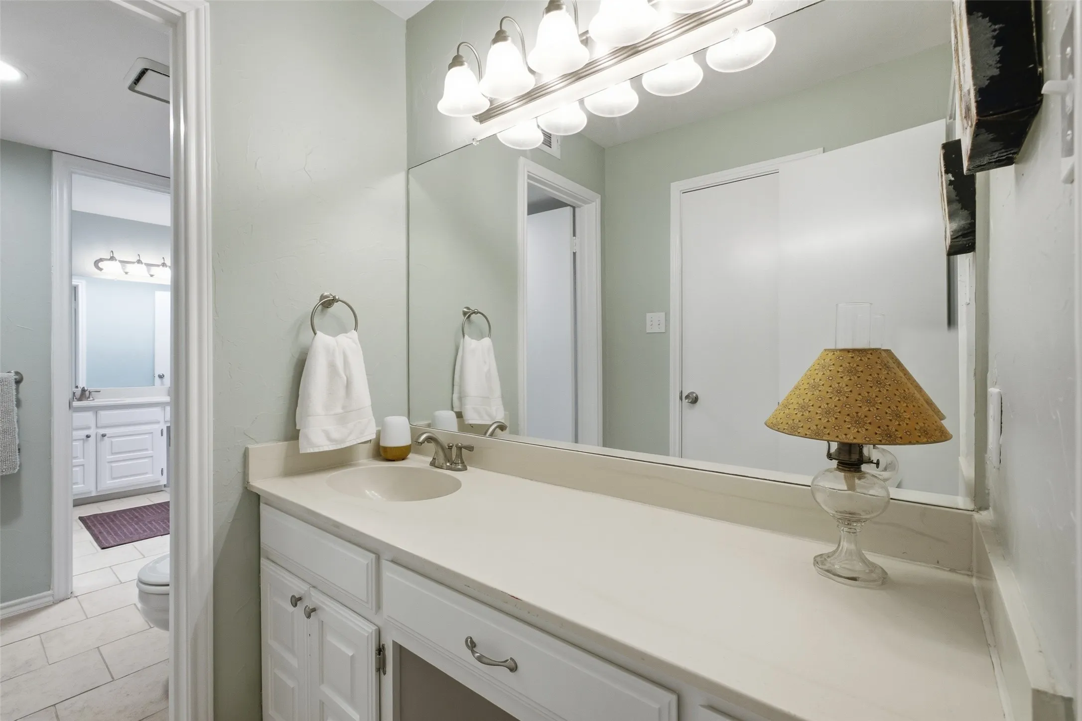 The upper hall bath connects through to a second vanity area, giving the upstairs bedrooms a comfortable amount of bathroom access without anyone sharing a sink.