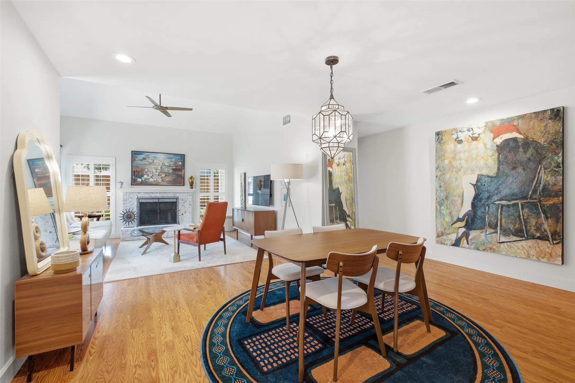 The dining and living areas flow together in one open, light-filled space. Hardwood floors, recessed lighting, and a statement geometric pendant fixture make this a room that works for everyday life and entertaining alike.