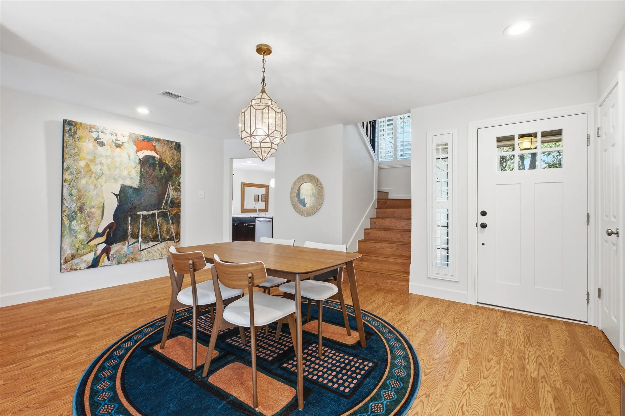 The dining area from another angle, showing the beautiful pendant light, wood floors, and the easy connection to the front entry and staircase beyond.