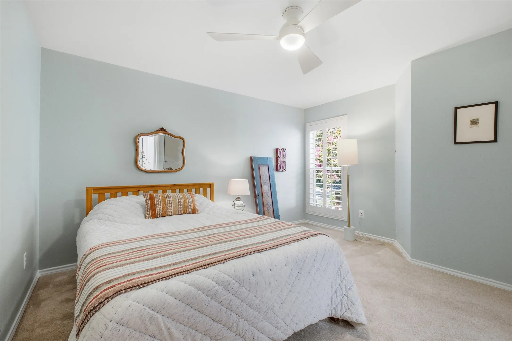 The second bedroom upstairs is comfortable and well-proportioned, with plantation shutters, a ceiling fan, and soft neutral walls. A good guest room, a good kids' room, or anything in between.