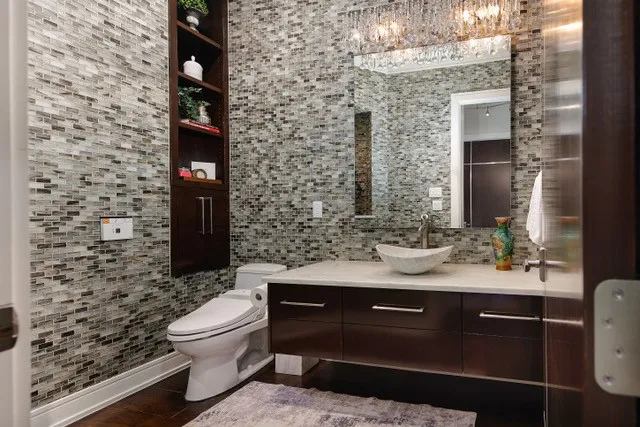 Wall-mounted vanity with a vessel sink, full-height tile, built-in shelving, a modern toilet, and wood-finish flooring