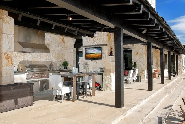 Expansive outdoor patio featuring light-toned stone flooring and natural stone wall construction