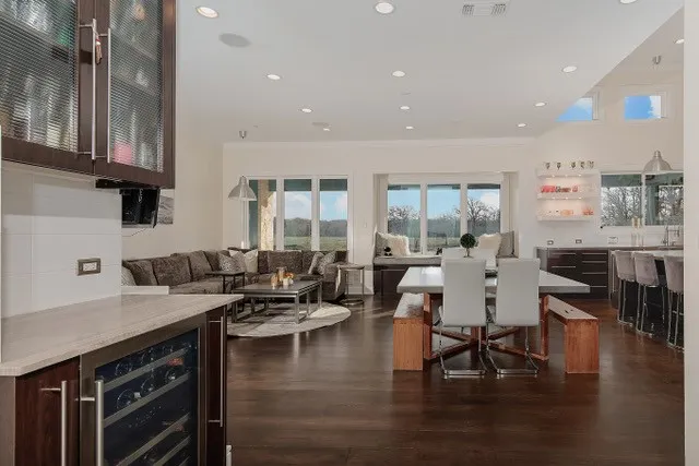 Open-concept living space featuring wood-finish flooring, recessed lighting, and large windows with a built-in window seat