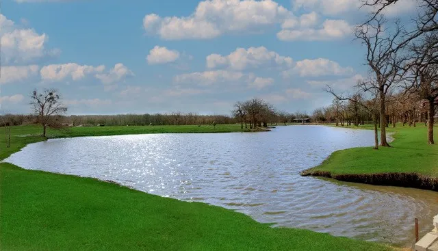 Expansive natural water feature with surrounding green lawns and mature trees