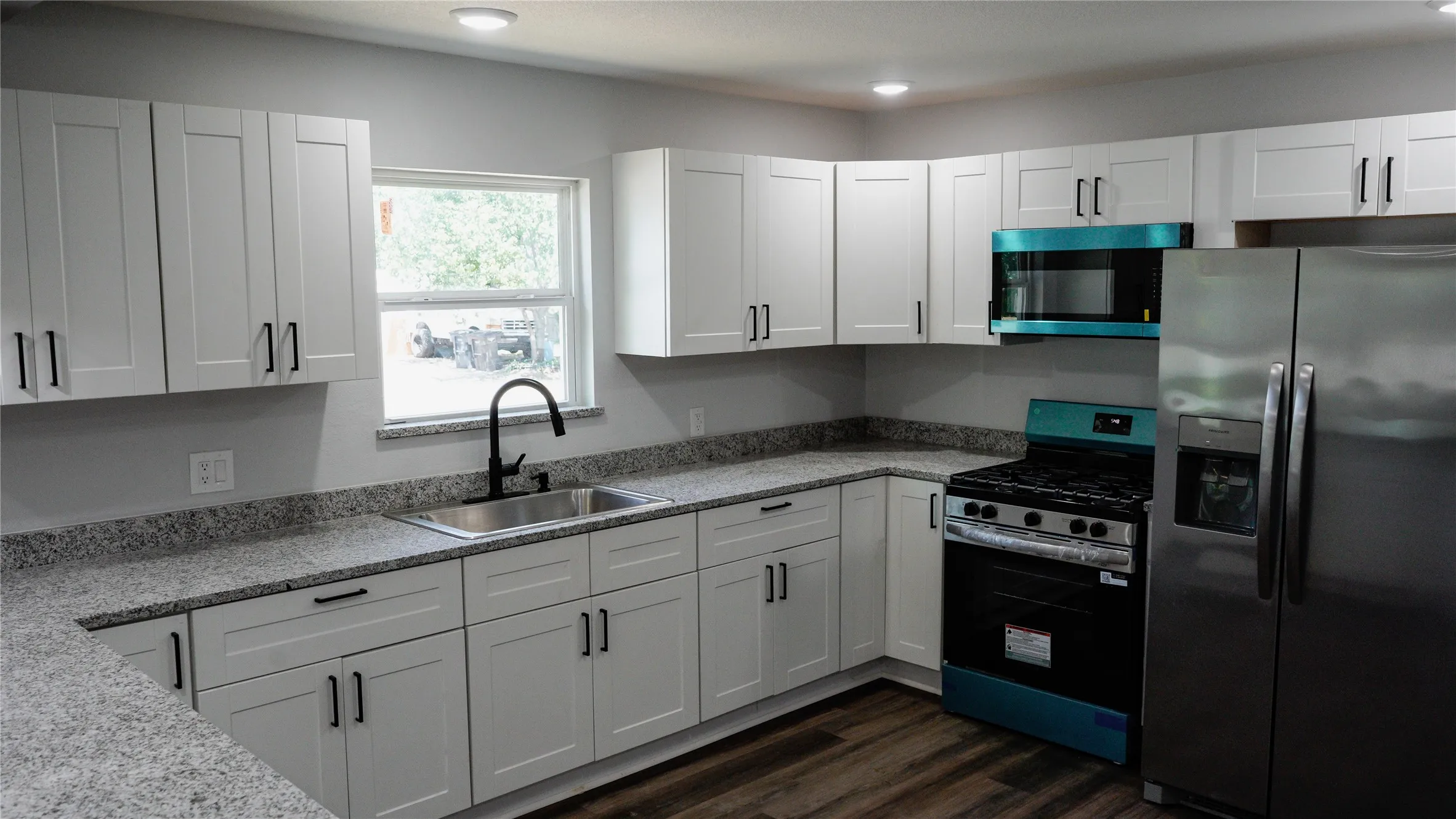 Kitchen featuring white shaker-style cabinetry, dark wood-finish flooring, light-toned countertops, and stainless steel​​‌​​​​‌​​‌‌​‌‌​​​‌‌​‌​‌​‌​​​‌​​ appliances