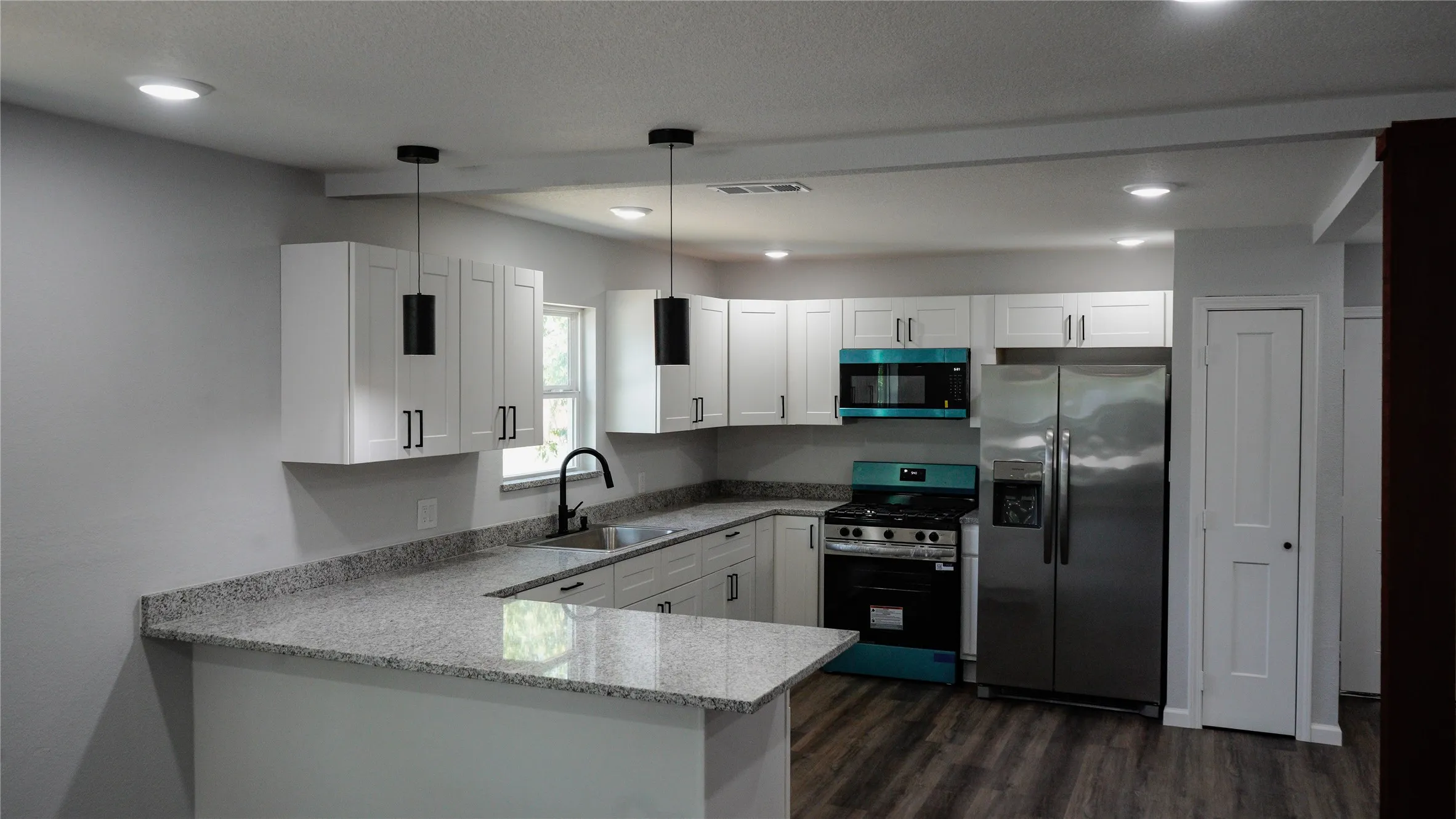 Kitchen featuring white cabinetry, light-toned countertops, stainless steel appliances, and dark wood-finish flooring