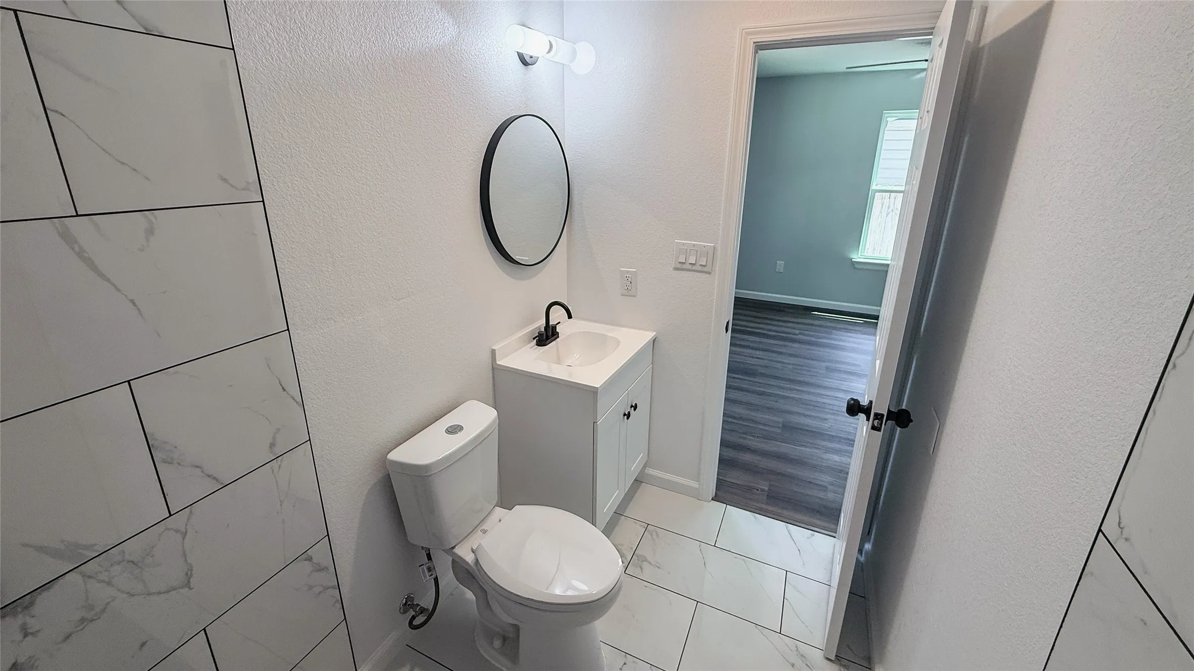 White vanity with a black faucet and a circular mirror