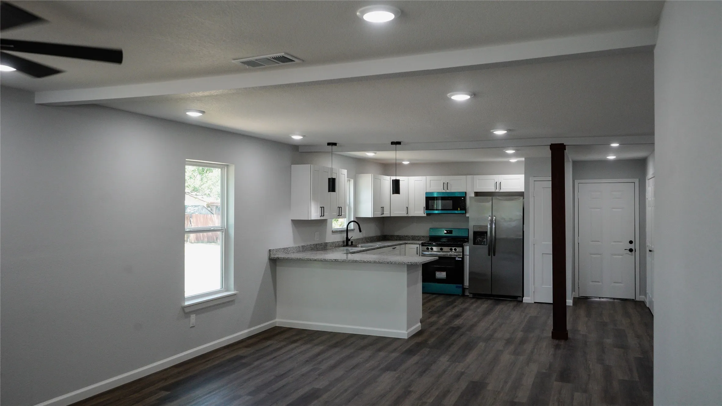Open-concept living area featuring wood-finish flooring, recessed lighting, and a ceiling fan