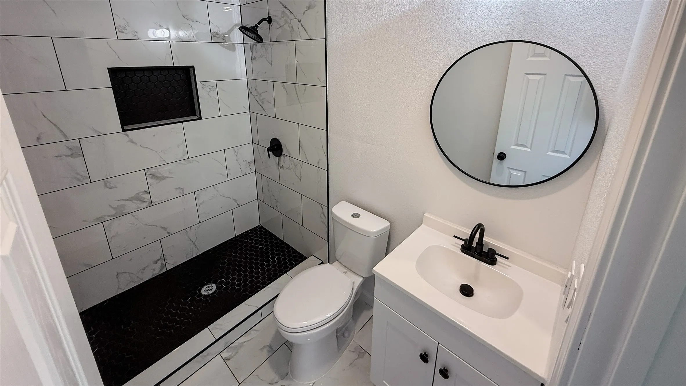 Walk-in shower with large format wall tile and hexagonal floor tile
