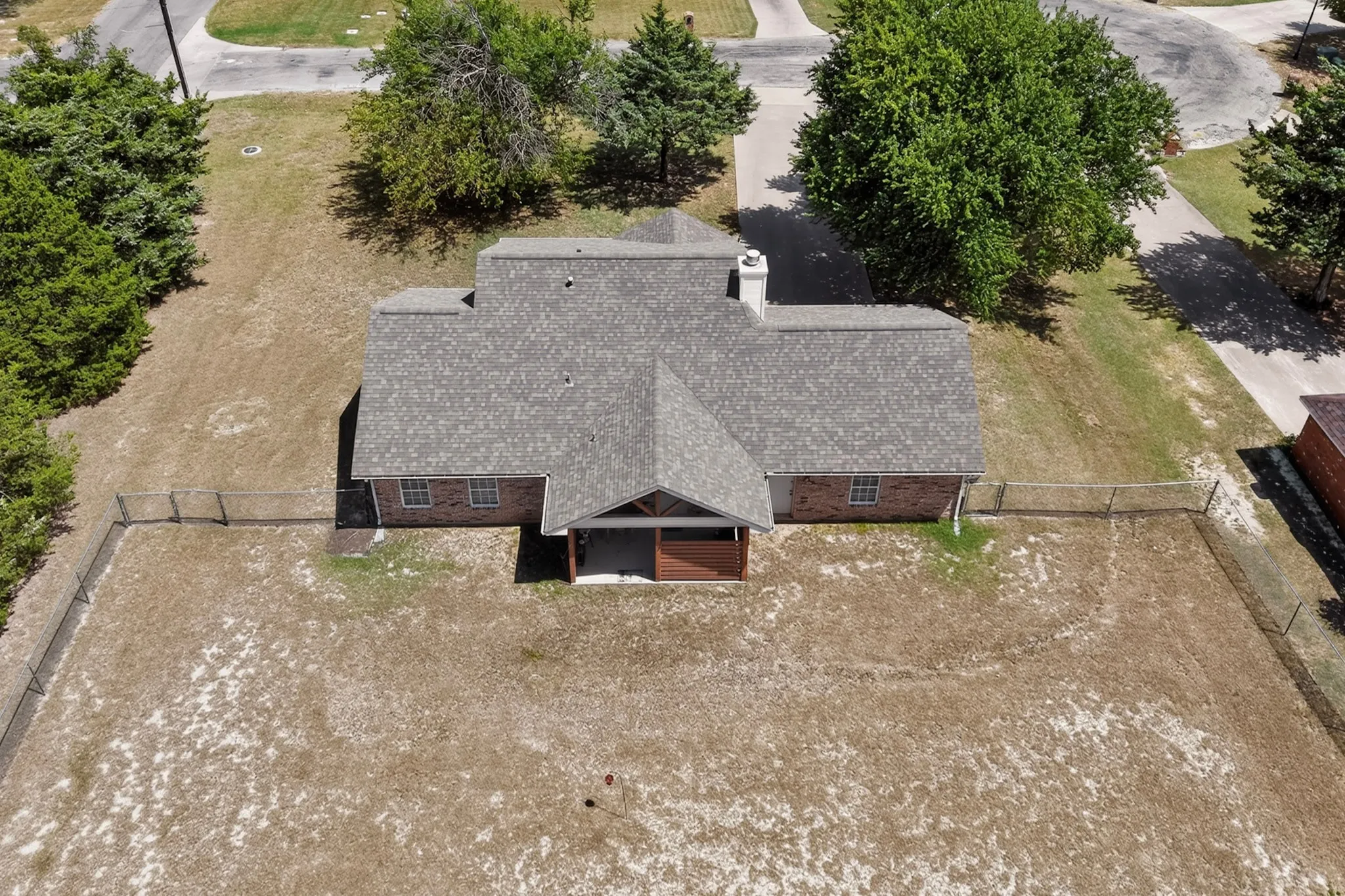 Brick exterior residence with a covered front porch, asphalt shingle roof, and a fenced perimeter