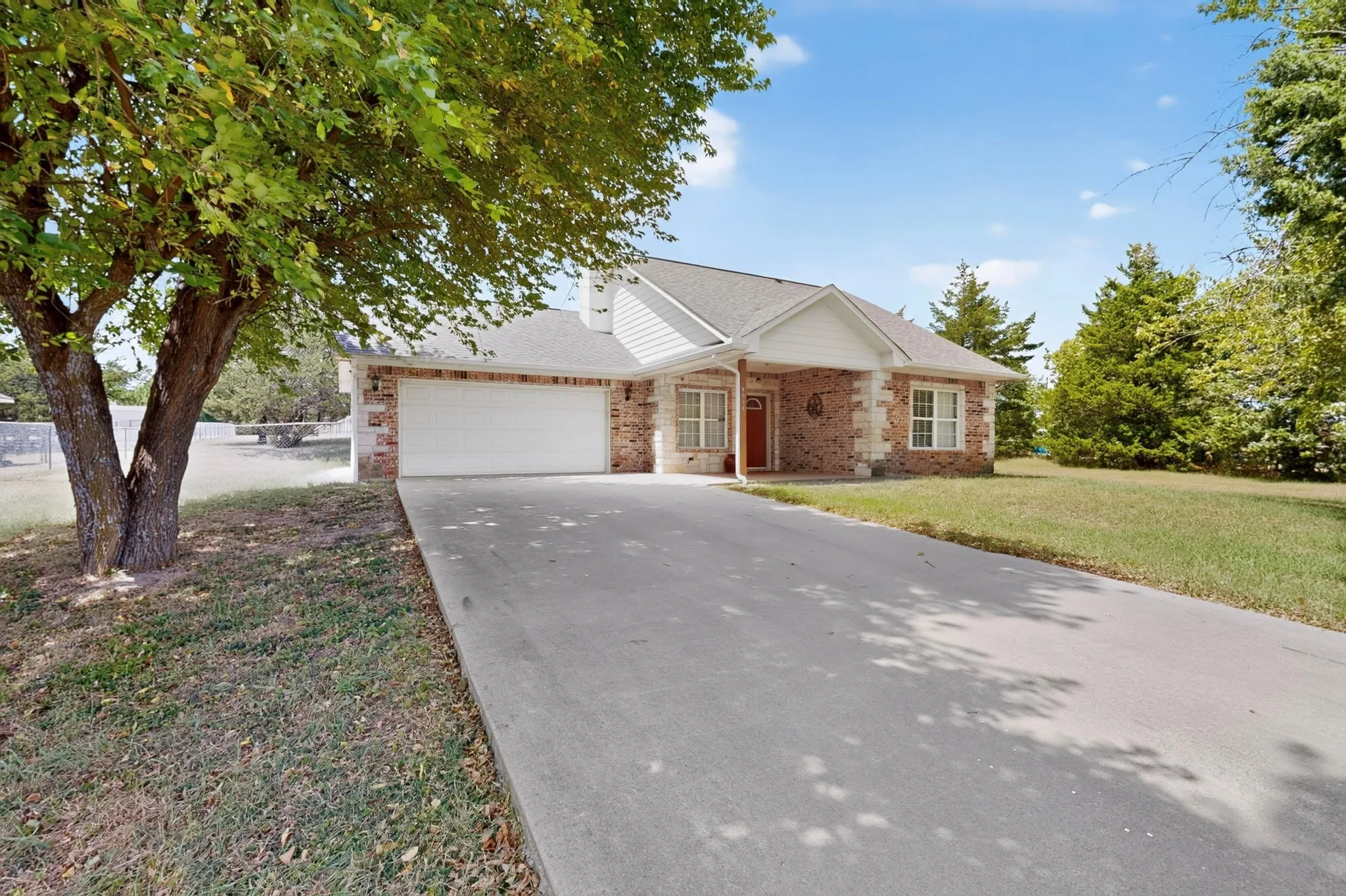 Brick and stone exterior with a white garage door, concrete driveway, and covered entry