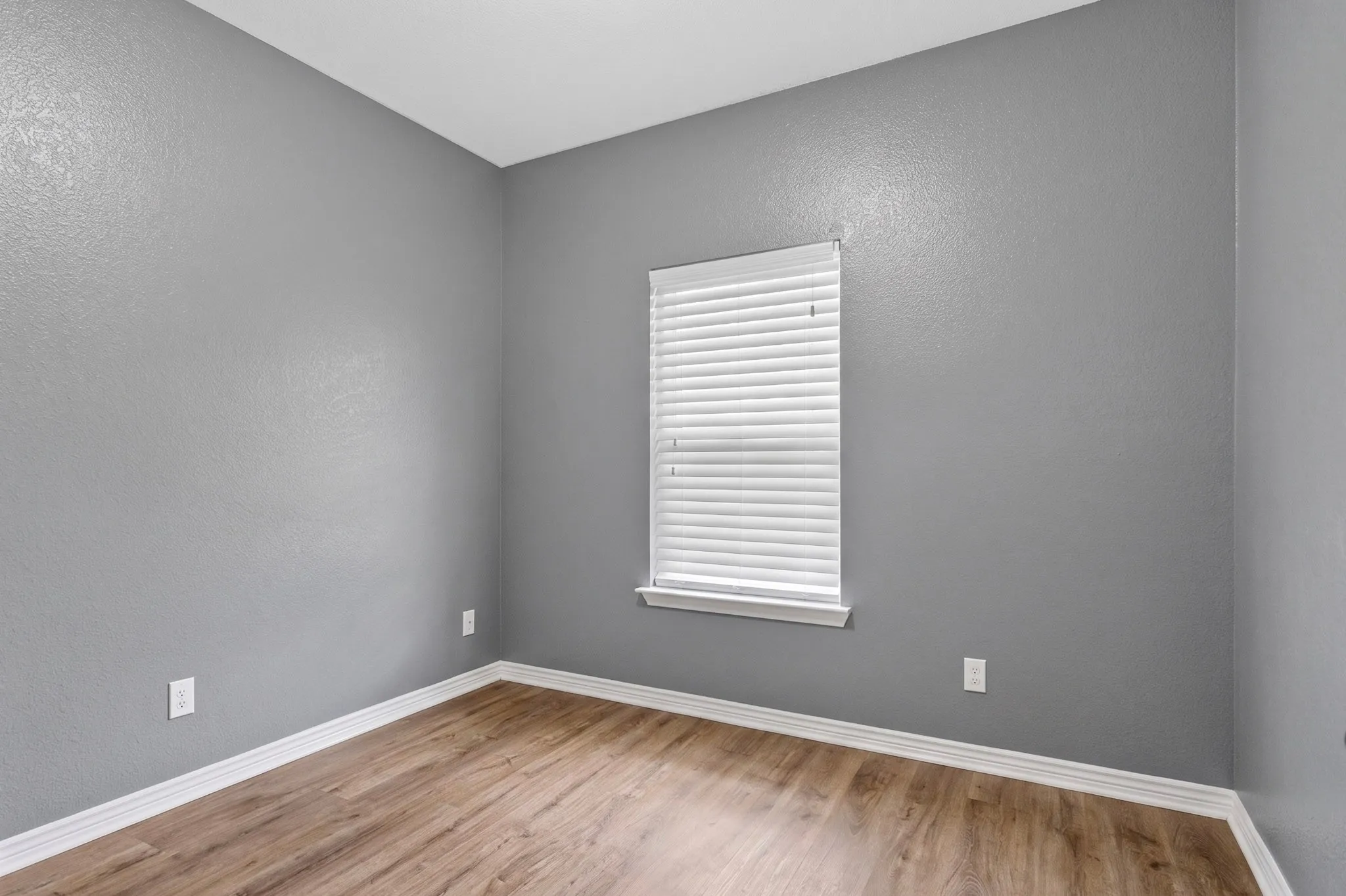 Wood-finish flooring, neutral gray wall tones, and white trim