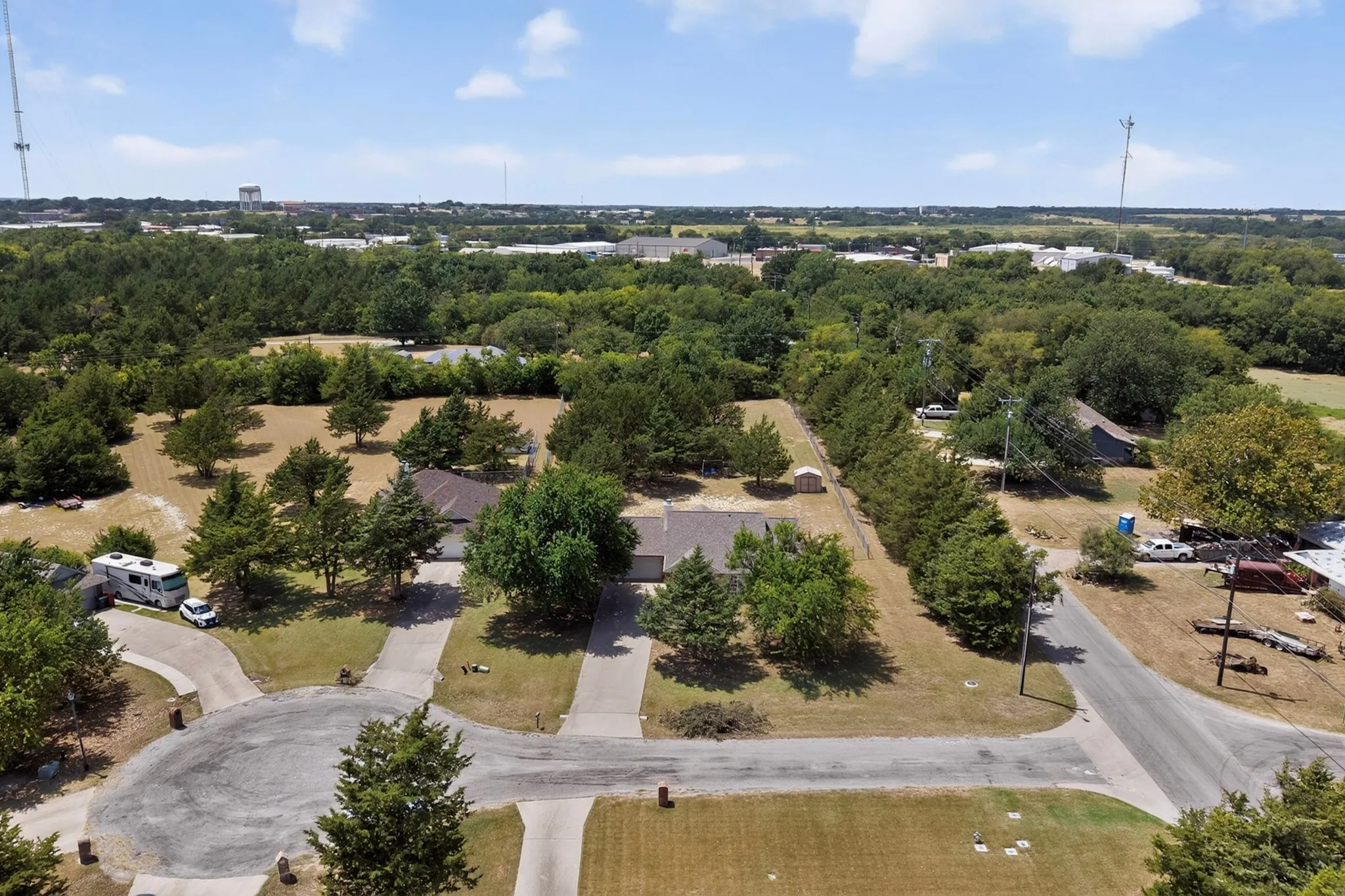 Expansive property with mature trees, green landscaping, and a paved driveway