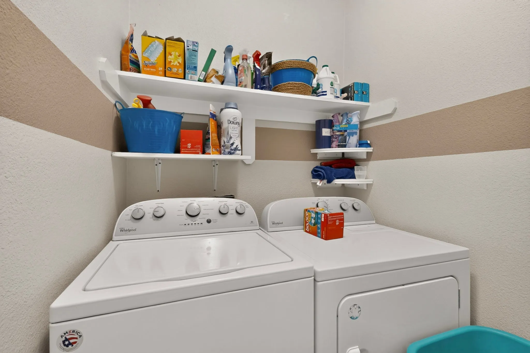 Laundry area featuring a washer, dryer, and wall-mounted shelving for storage