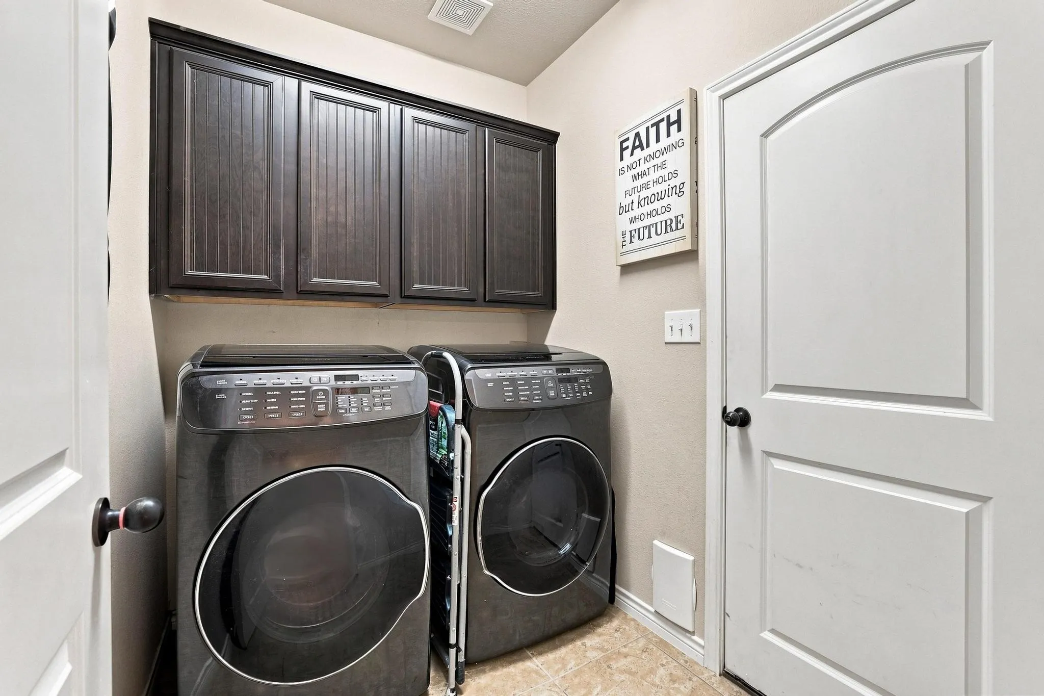 Built-in cabinetry with dark wood finish, durable tile flooring, and a solid core interior door with arch detail