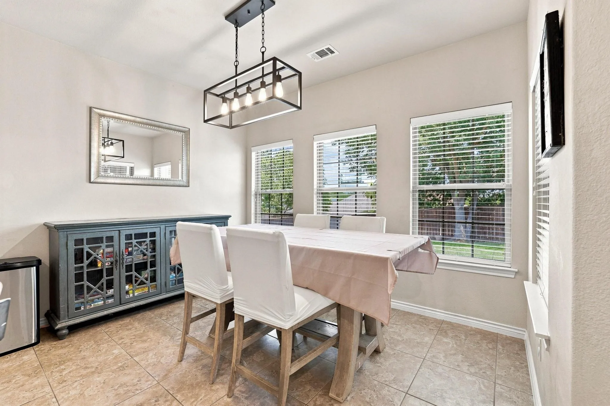 Tile flooring with a neutral finish, multiple windows with blinds, and a contemporary chandelier