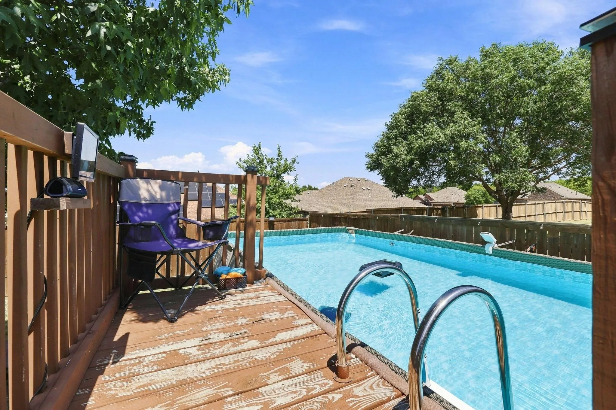 Outdoor deck with a built-in swimming pool, wood railing, and metal pool handrails