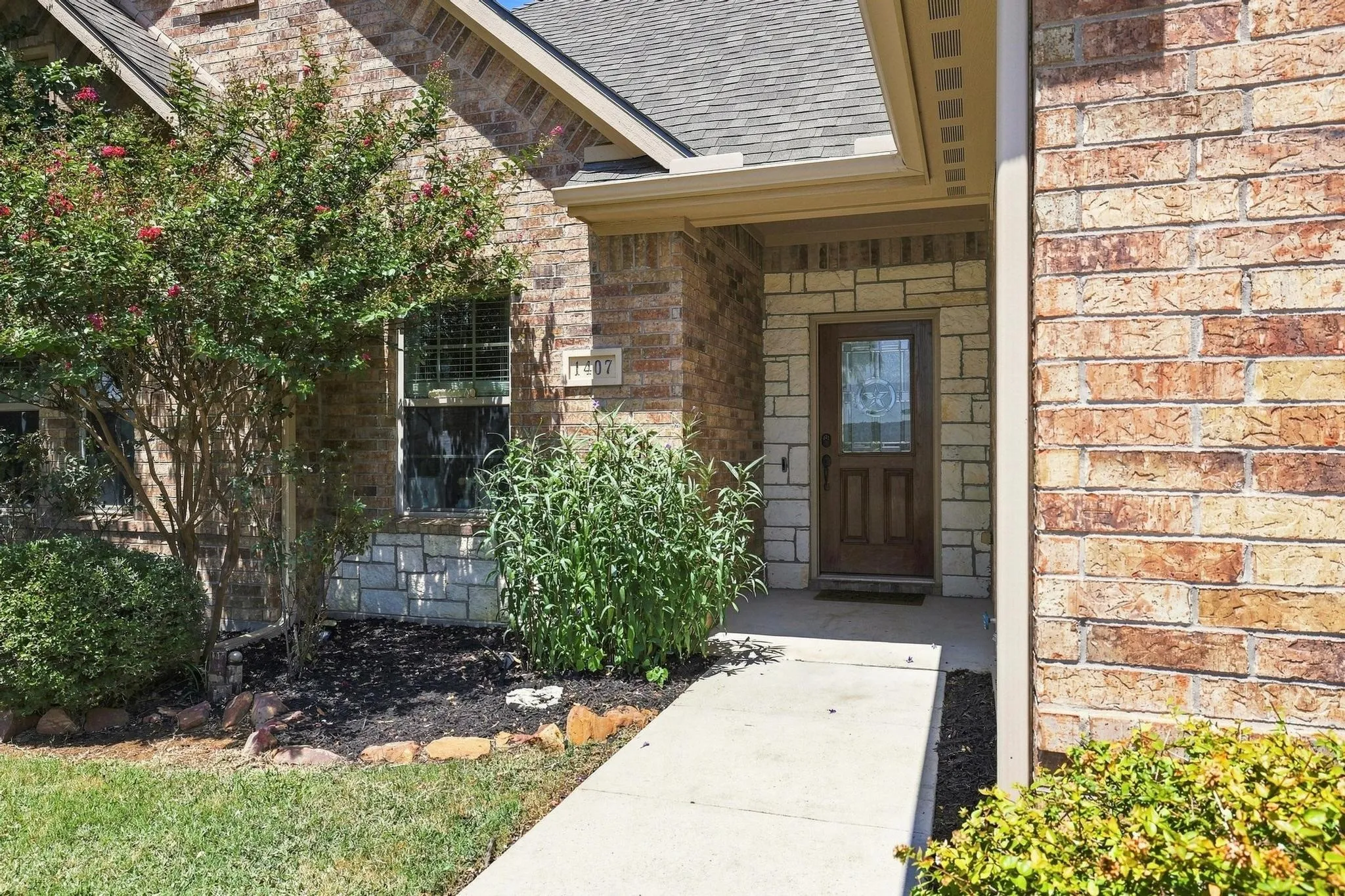 Brick exterior with stone accents, covered entry, and a paneled front door with glass insert