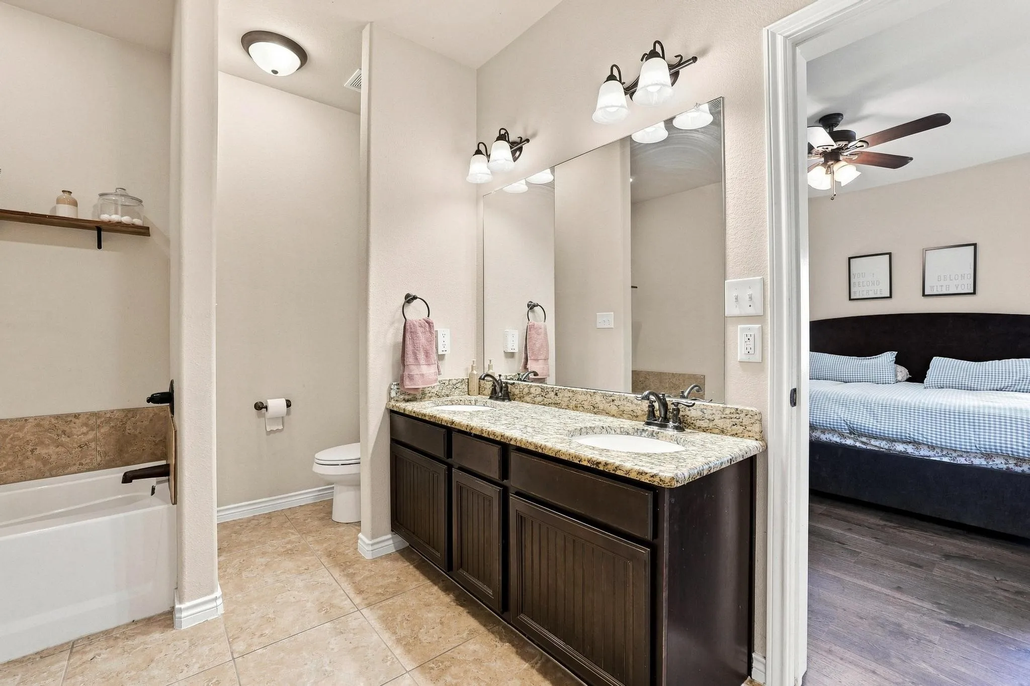 Double vanity with integrated sinks, granite-finish countertop, and dark wood-finish cabinetry