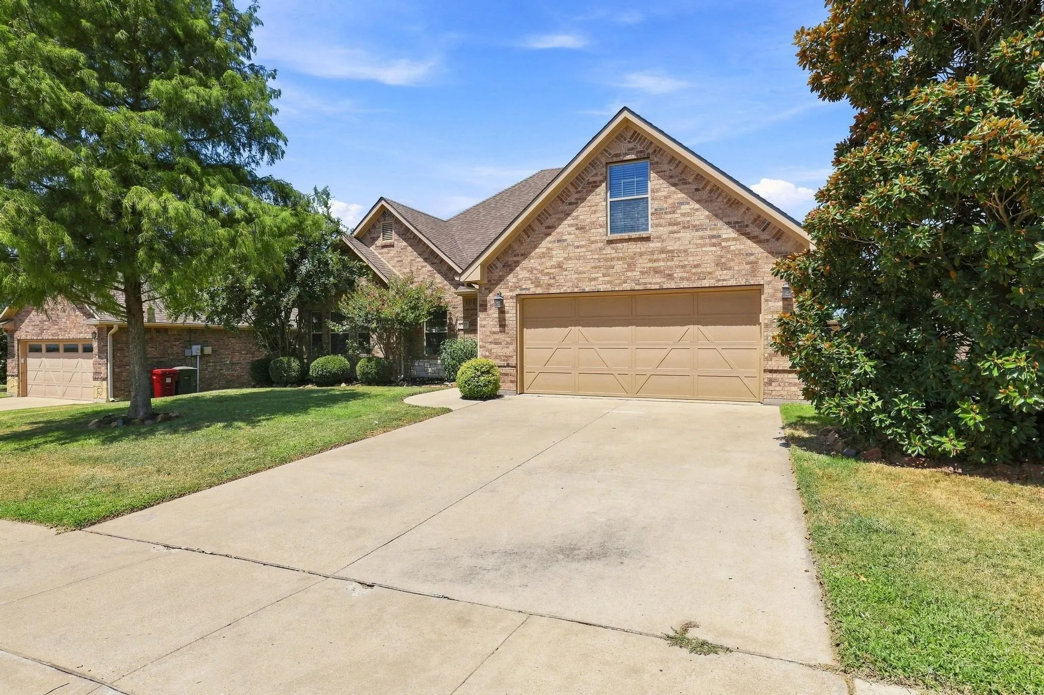 Brick exterior with a gabled roofline, concrete driveway, and attached garage