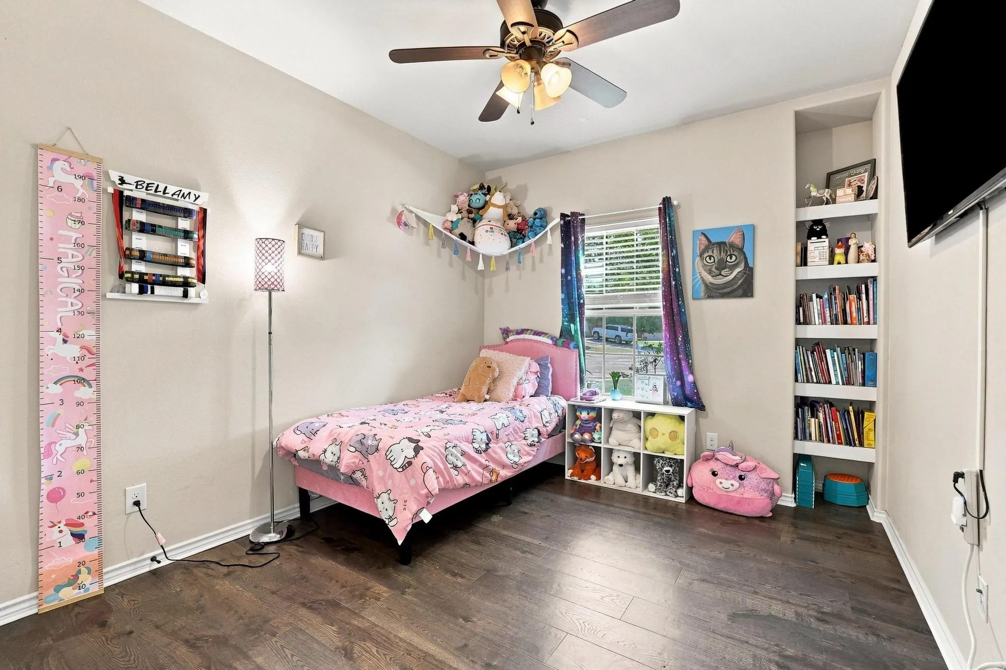 Wood-finish flooring, built-in shelving, ceiling fan with light fixture, and window with blinds
