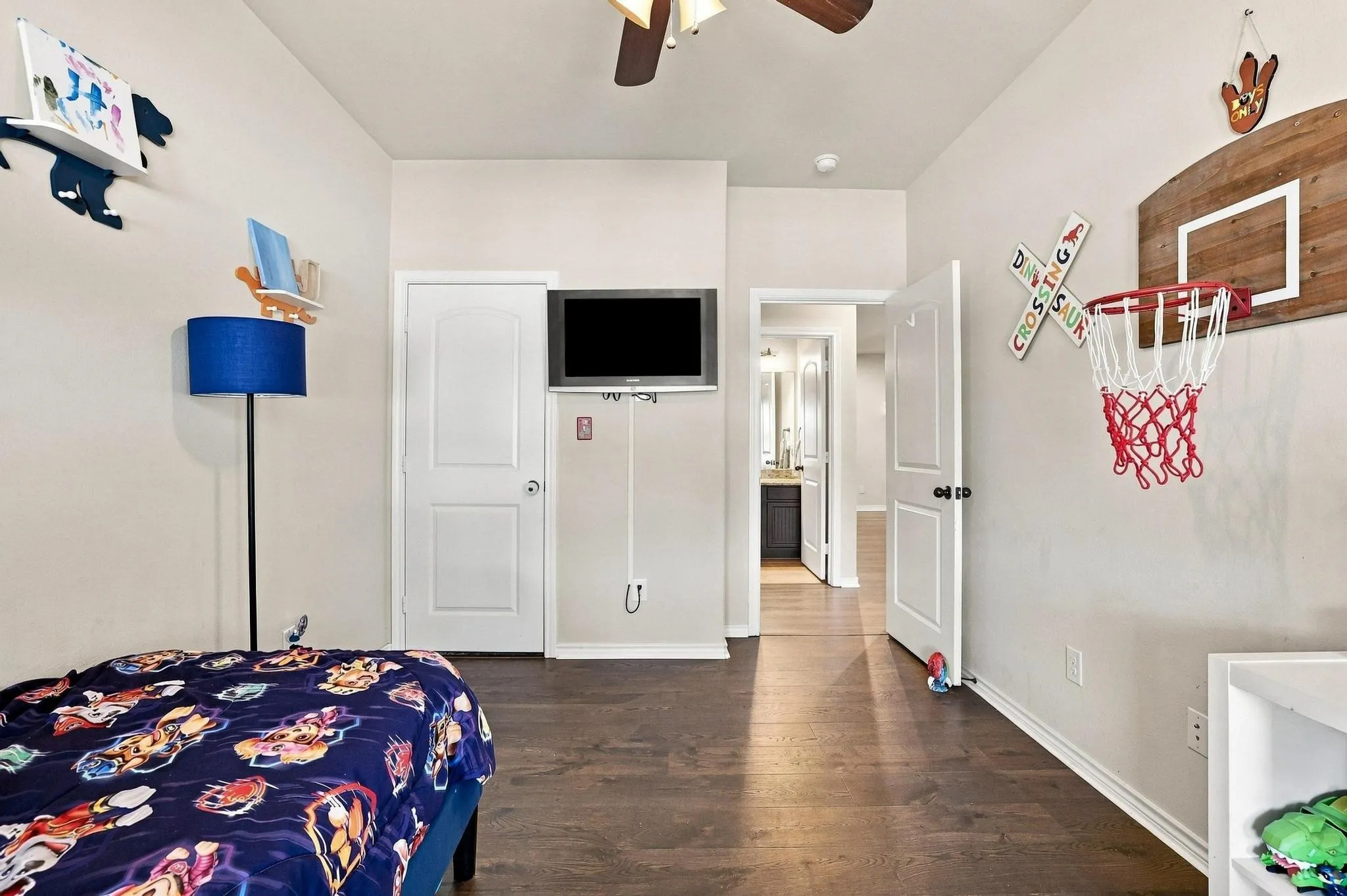 Hardwood-finish flooring, white trim, interior paneled doors, ceiling fan, and wall-mounted television