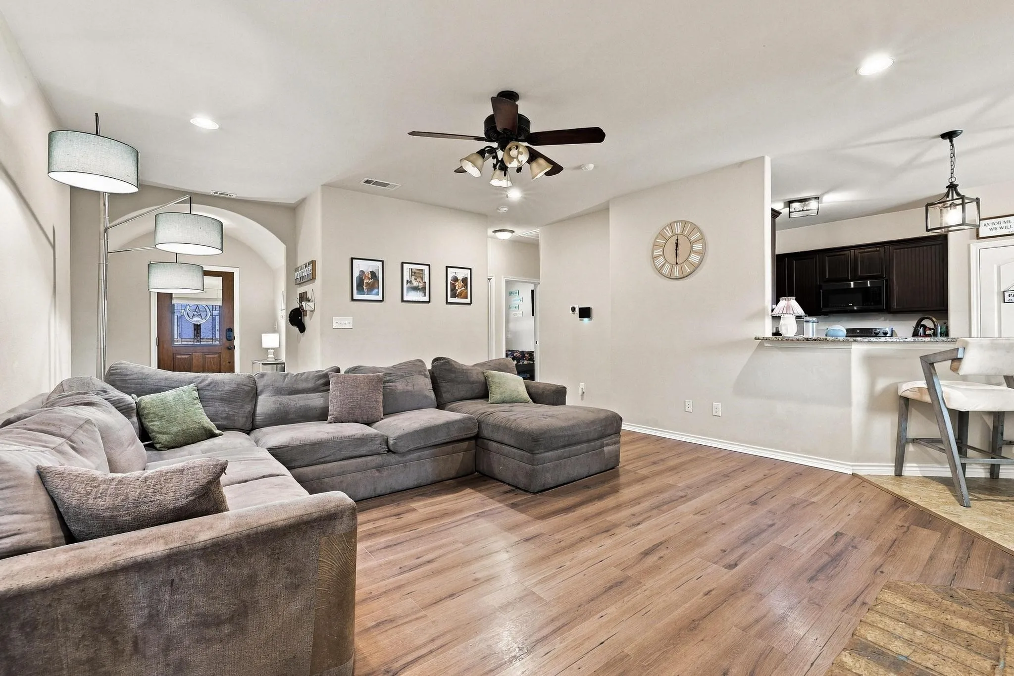 Wood-finish flooring, recessed lighting, ceiling fan, arched doorway, and a kitchen pass-through with counter seating