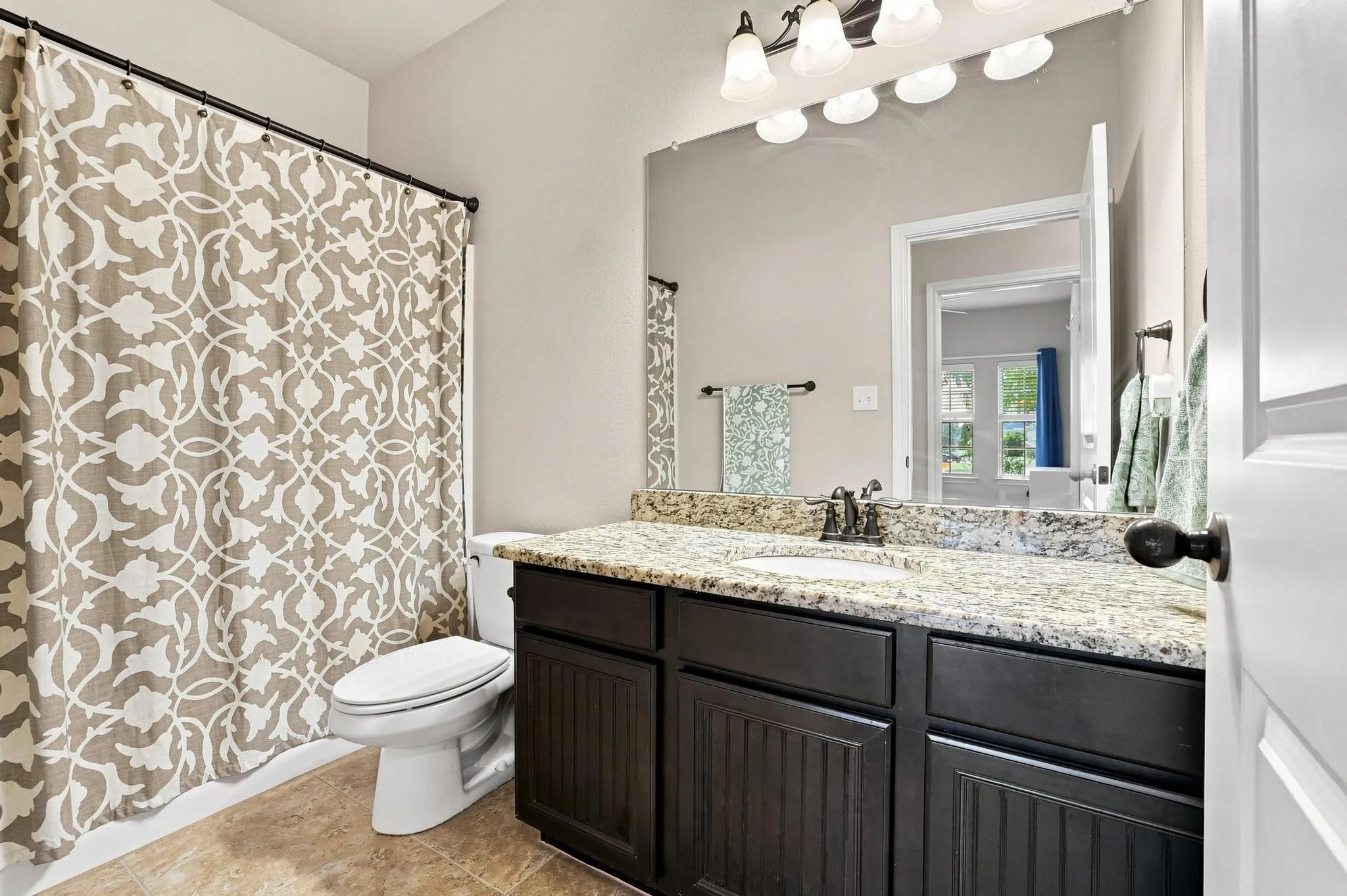 Bathroom featuring a built-in vanity with a granite-style countertop, undermount sink, and dark wood-finish cabinetry