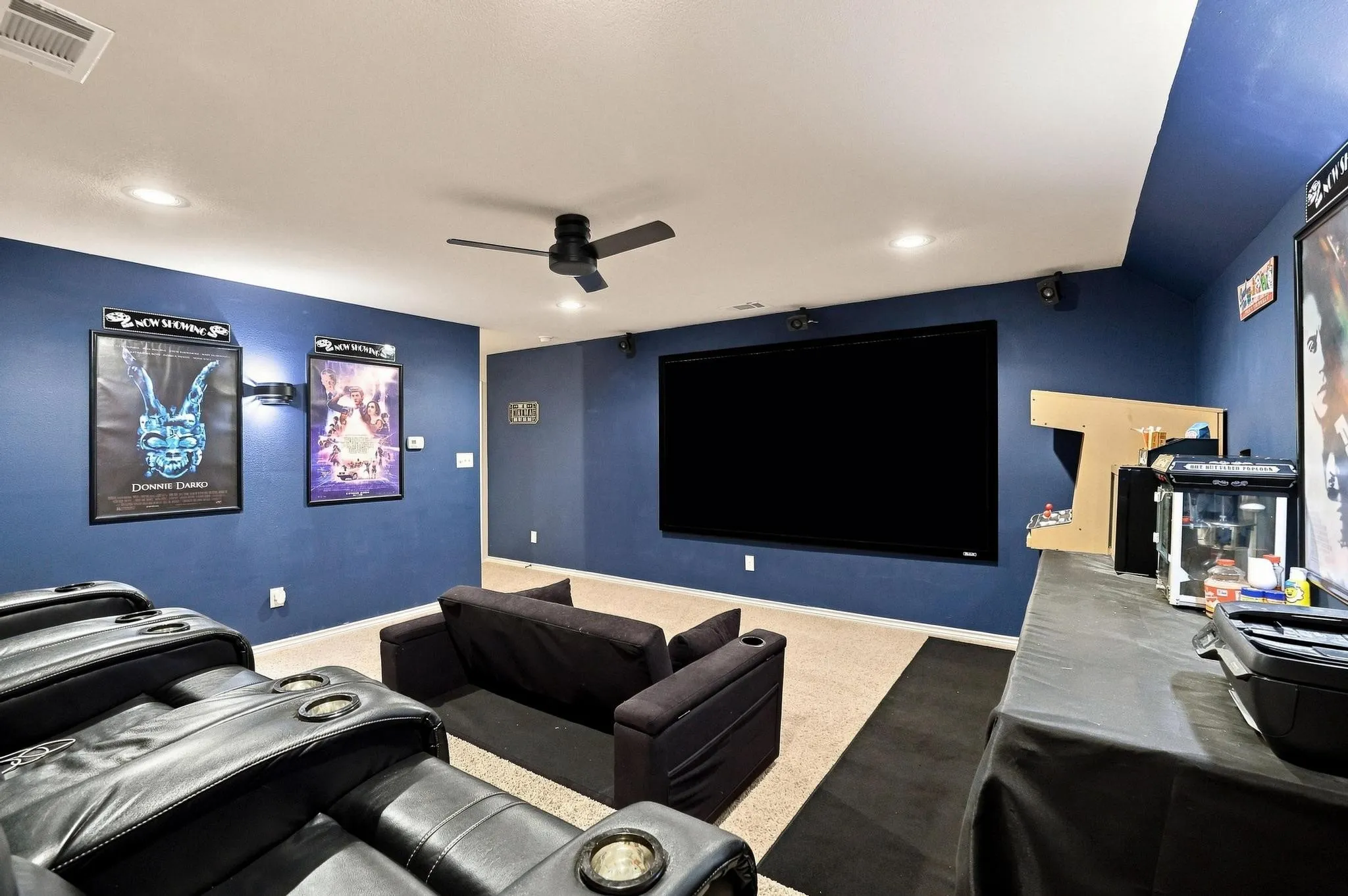 Media room featuring a large screen display, recessed lighting, ceiling fan, and wall-mounted speakers