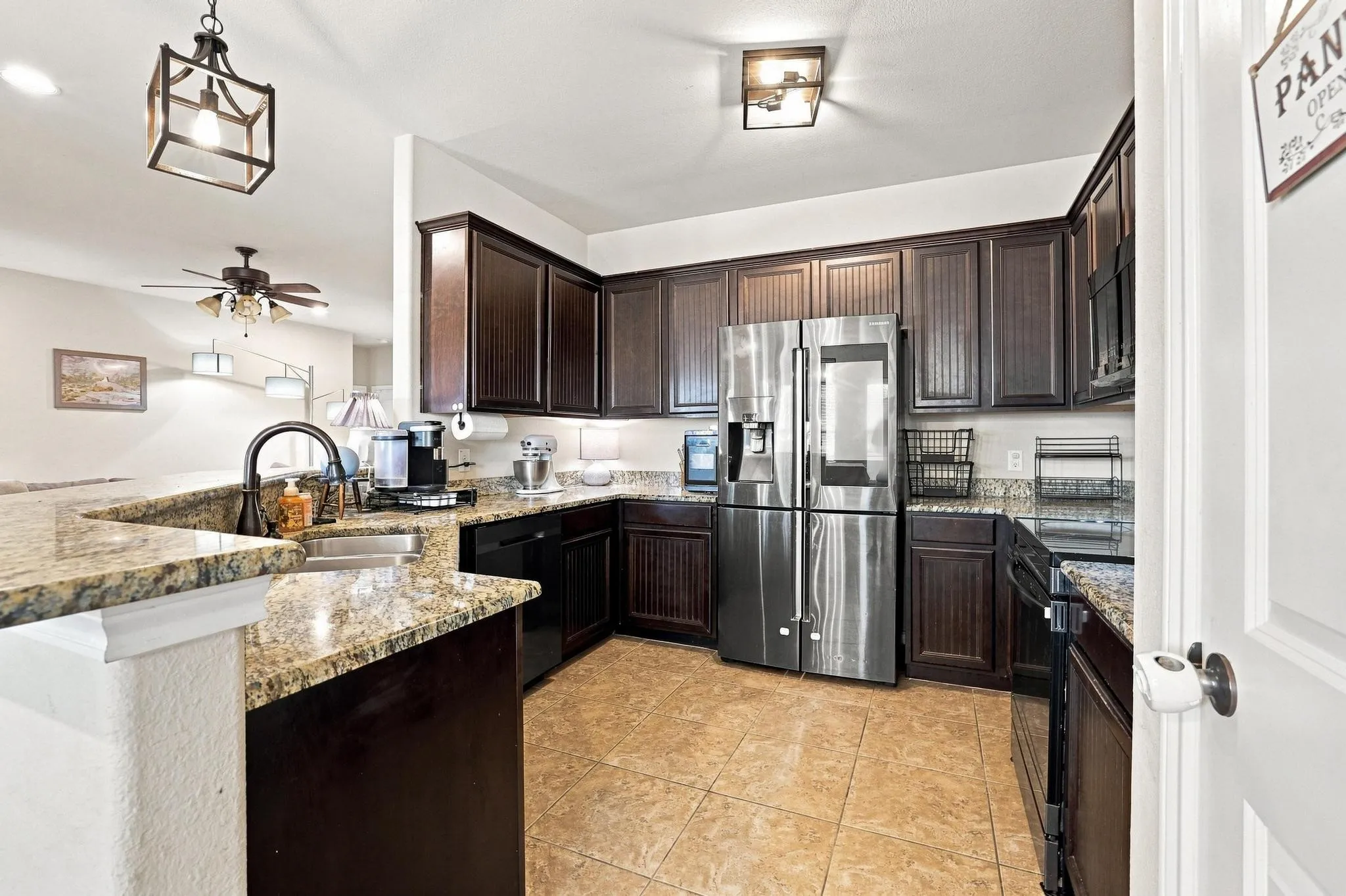 U-shaped kitchen with dark wood-finish cabinetry, light-toned granite countertops, and stainless steel appliances